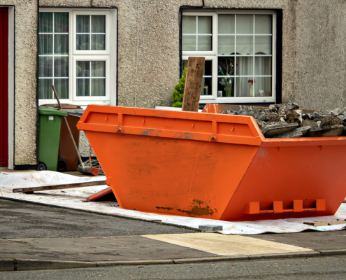 One orange color skip full of rubbish in front of a house ready for collection