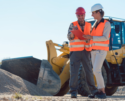 Man and woman worker on construction site talking about a dump box